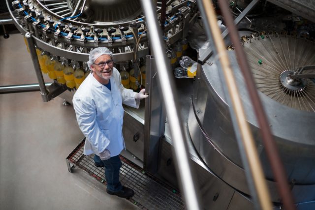 Factory engineer monitoring filled juice bottle